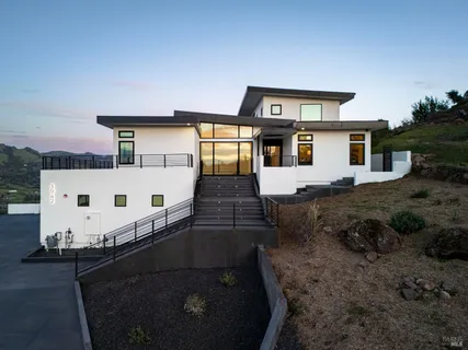 a aerial view of a house with garden space ocean and mountain view in back