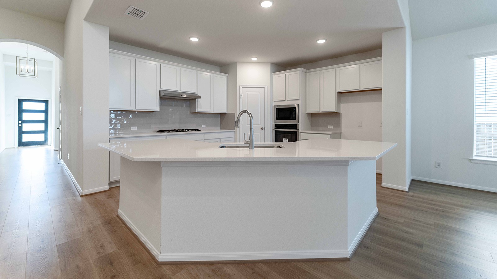 251 Grey Leaf Road Buda, TX 78610 - Photo 5 of 17 Kitchen featuring arched walkways, white cabinets, decorative backsplash, a center island with sink, and recessed lighting