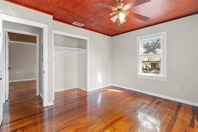 a view of an empty room with window and wooden floor