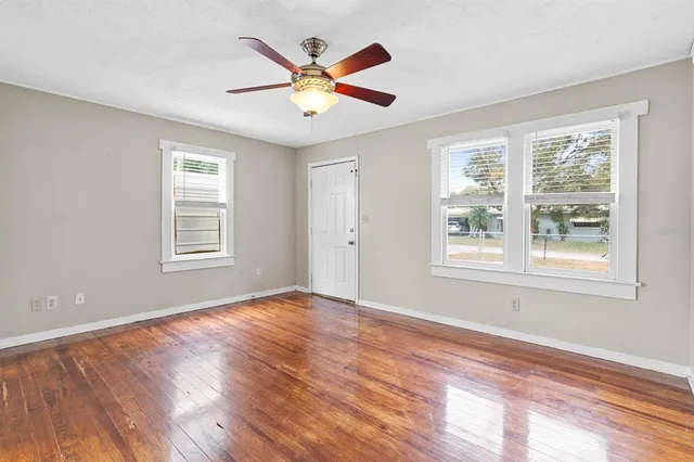 a view of an empty room with wooden floor and a window