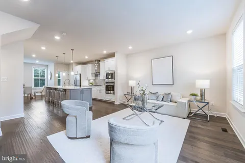 a large kitchen with stainless steel appliances a stove a sink dishwasher a microwave oven and a dining table with wooden floor