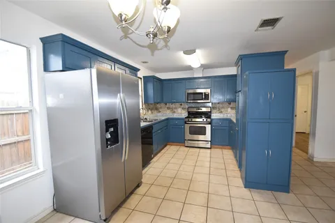 a kitchen with stainless steel appliances granite countertop a refrigerator a sink a stove top oven and cabinets