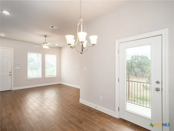 an empty room with wooden floor mirror and windows