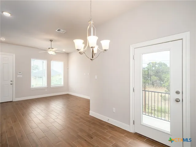 an empty room with wooden floor mirror and windows