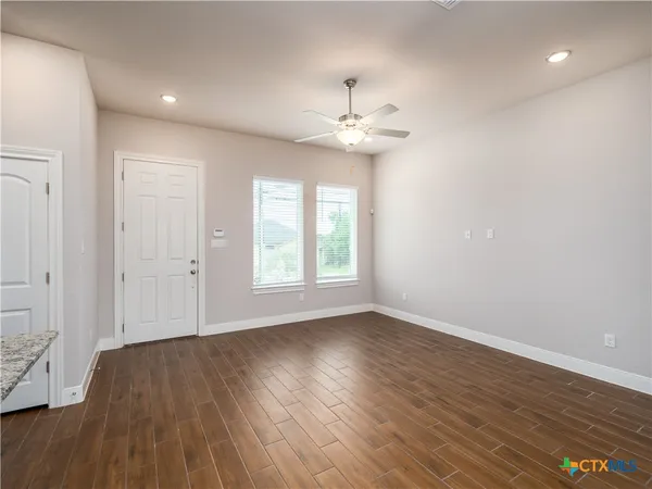 an empty room with wooden floor and windows