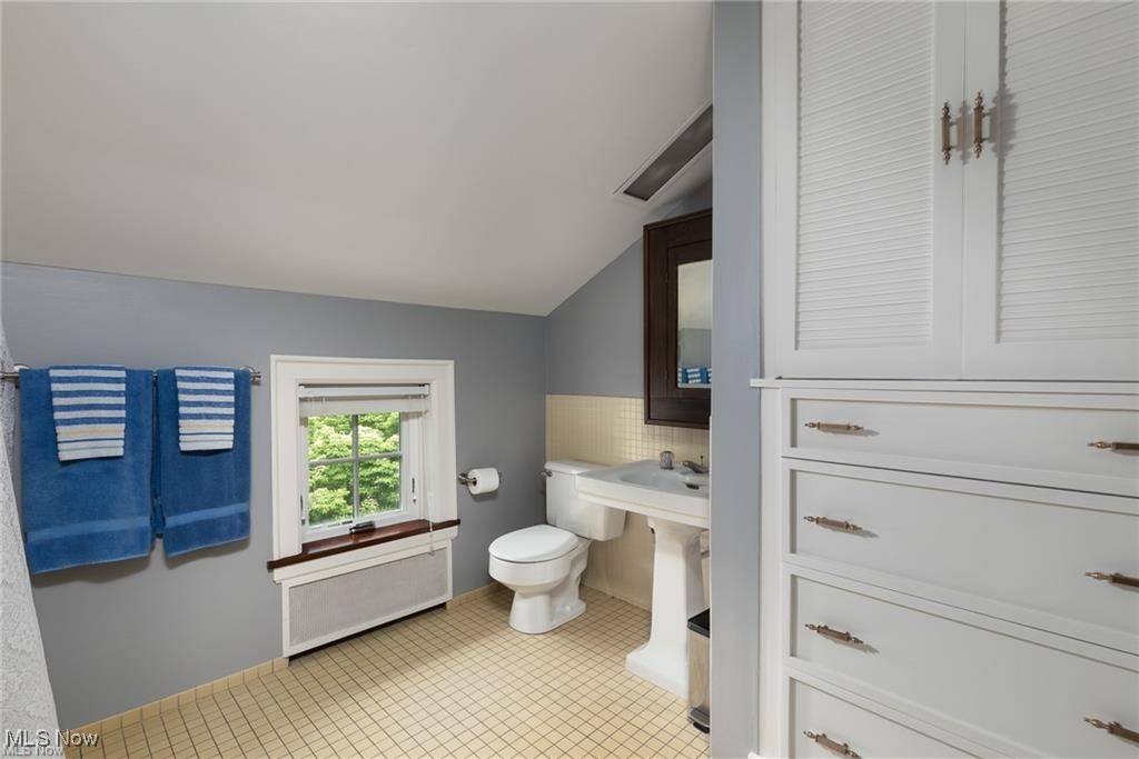 644 Riverside Drive Painesville, OH 44077 - Photo 18 of 48 Half bathroom featuring radiator, lofted ceiling, toilet, and tile patterned floors