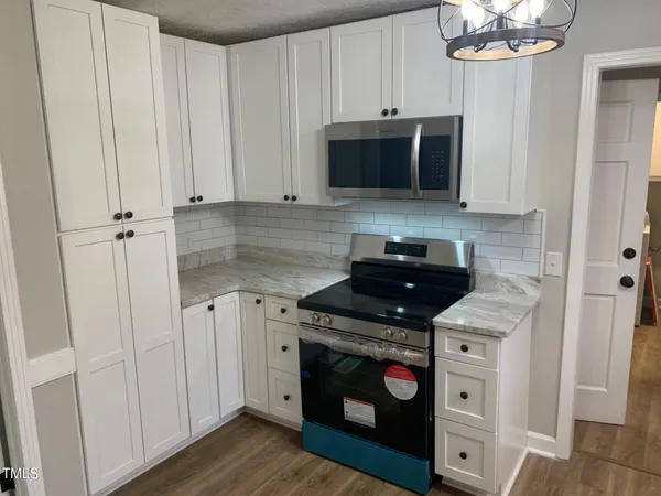 a kitchen with stainless steel appliances granite countertop a stove a microwave and a white cabinets