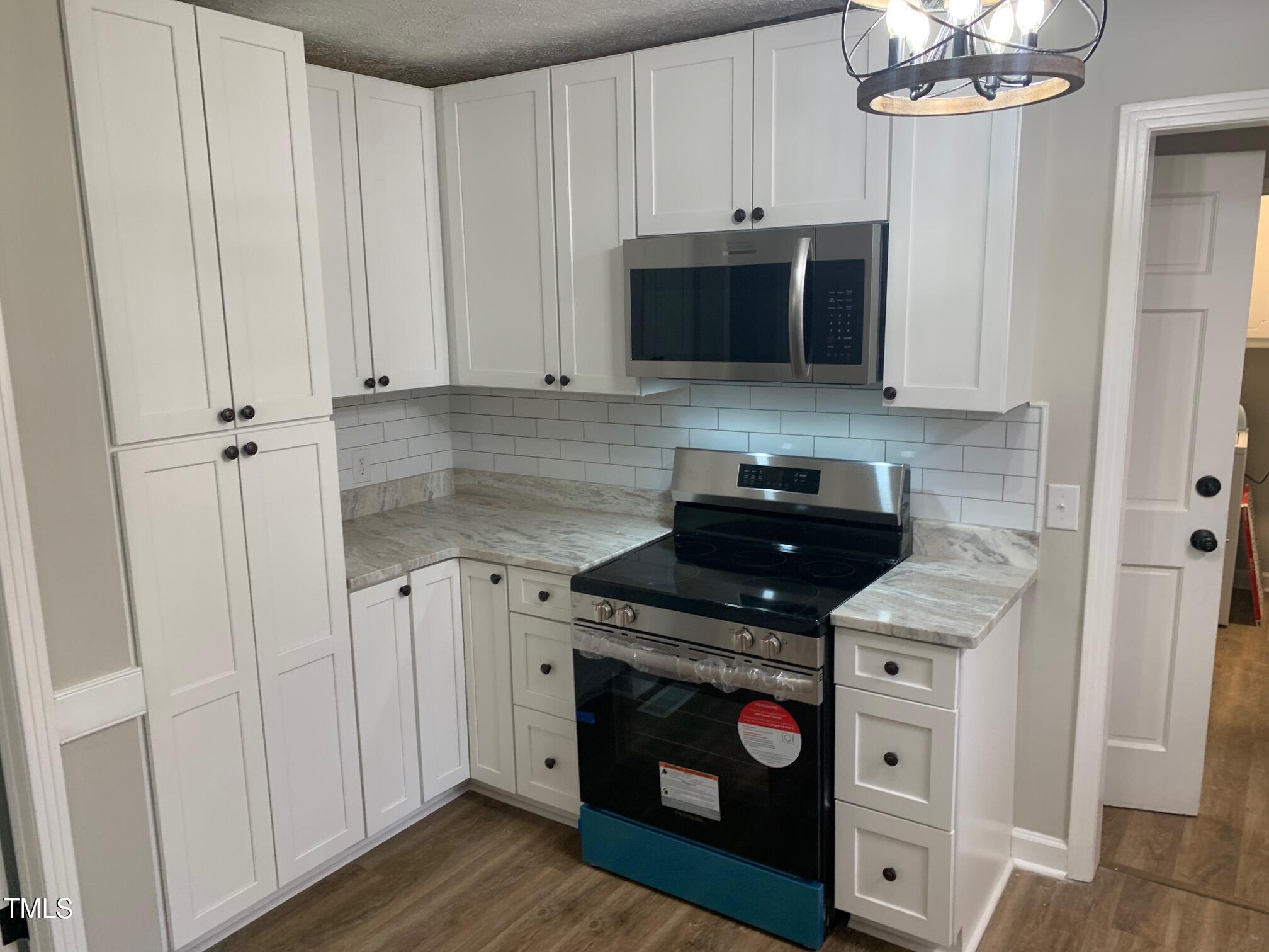 209 Reade Drive Roxboro, NC 27573 - Photo 8 of 19 a kitchen with stainless steel appliances granite countertop a stove a microwave and a white cabinets