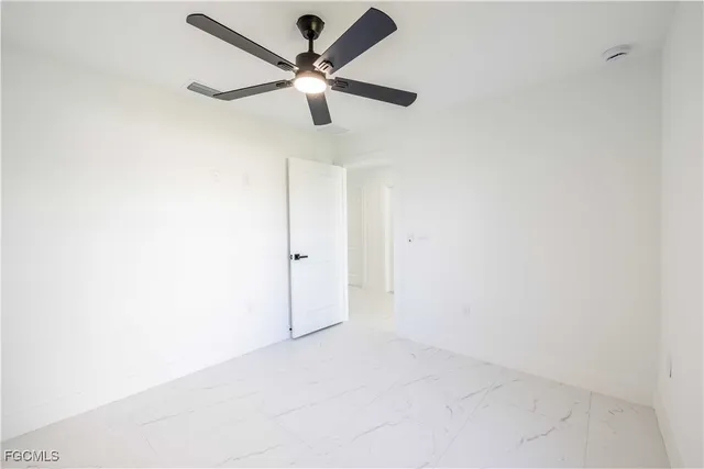 an empty room with window and ceiling fan