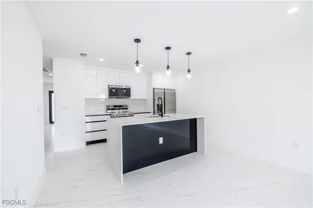 a kitchen with stainless steel appliances granite countertop a refrigerator a sink and a oven with white countertops