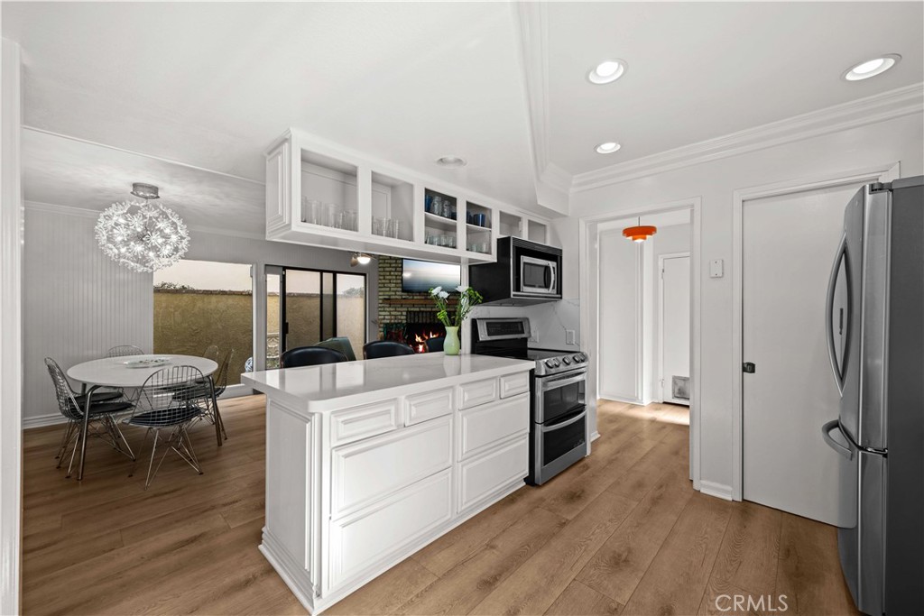 86 North Vía Di Roma Walk Long Beach, CA 90803 - Photo 19 of 42 a kitchen with stainless steel appliances a stove top oven a refrigerator a dining table and chairs with wooden floor