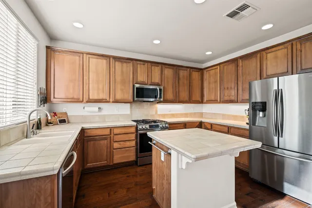 a kitchen with a sink a stove a refrigerator a center island and a window