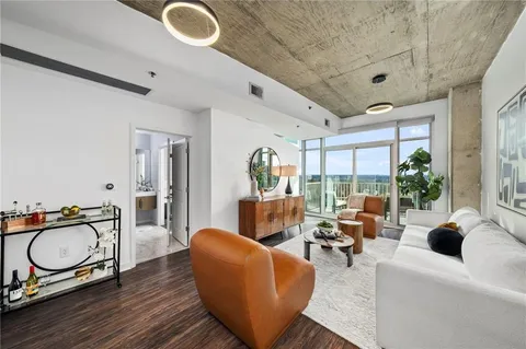a living room with furniture a rug potted plant and a large window