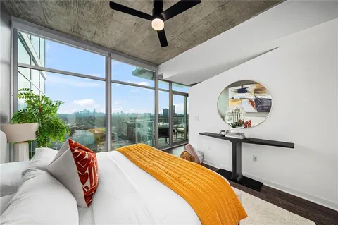 a bedroom with a bed a mirror on dresser and a large window