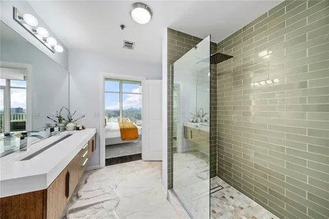 a spacious bathroom with a granite countertop sink a mirror and shower