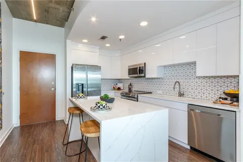 a kitchen with stainless steel appliances granite countertop a sink a stove a refrigerator cabinets and chairs