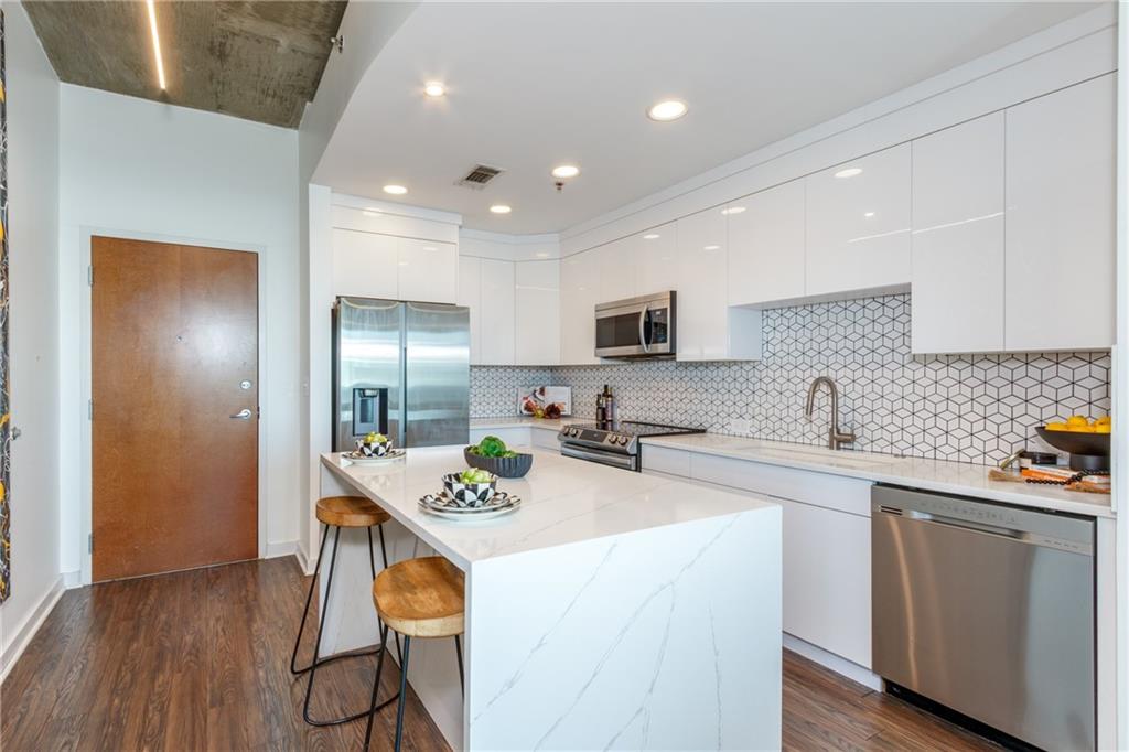 250 Pharr Road Northeast, Unit 1116 Atlanta, GA 30305 - Photo 3 of 45 a kitchen with stainless steel appliances granite countertop a sink a stove a refrigerator cabinets and chairs
