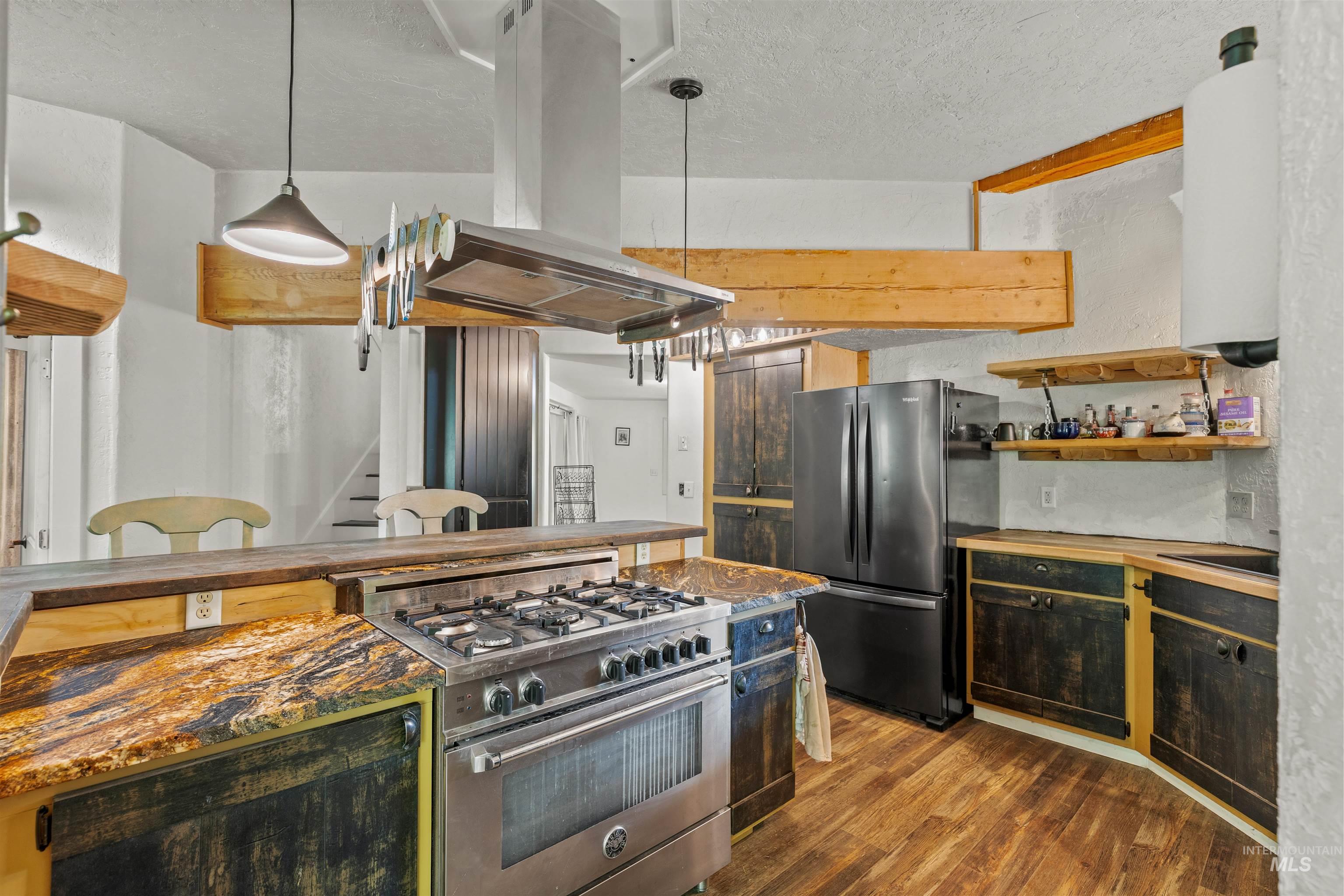 1314 Cedar Ridge Road Kendrick, ID 83537 - Photo 19 of 50 Kitchen featuring a stainless steel range with a built-in hood, dark-toned cabinetry, wood-finish flooring, and natural wood beams