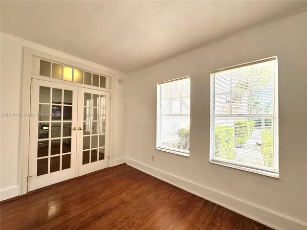 a view of an empty room with a window and wooden floor