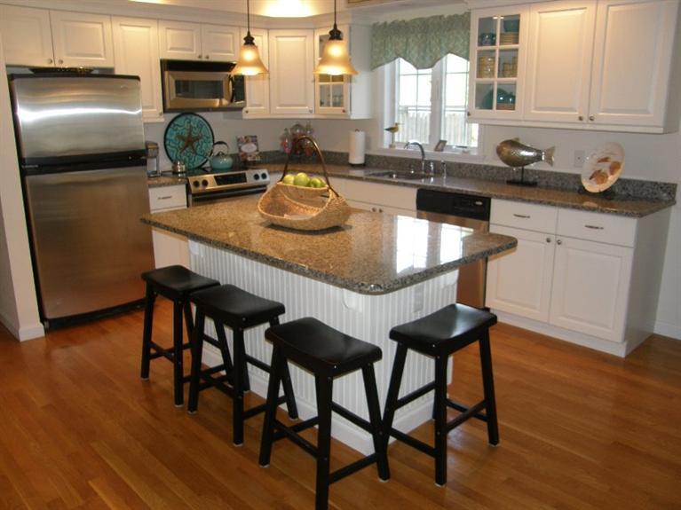 9 Shady Lane Chatham, MA 02633 - Photo 3 of 15 a kitchen with stainless steel appliances granite countertop a table chairs in it and wooden floors