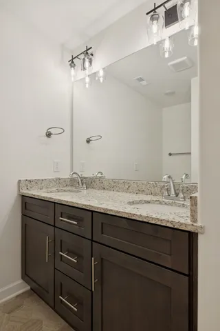 a bathroom with a granite countertop sink a light fixture and a mirror