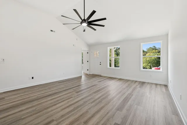 an empty room with wooden floor window and ceiling fan