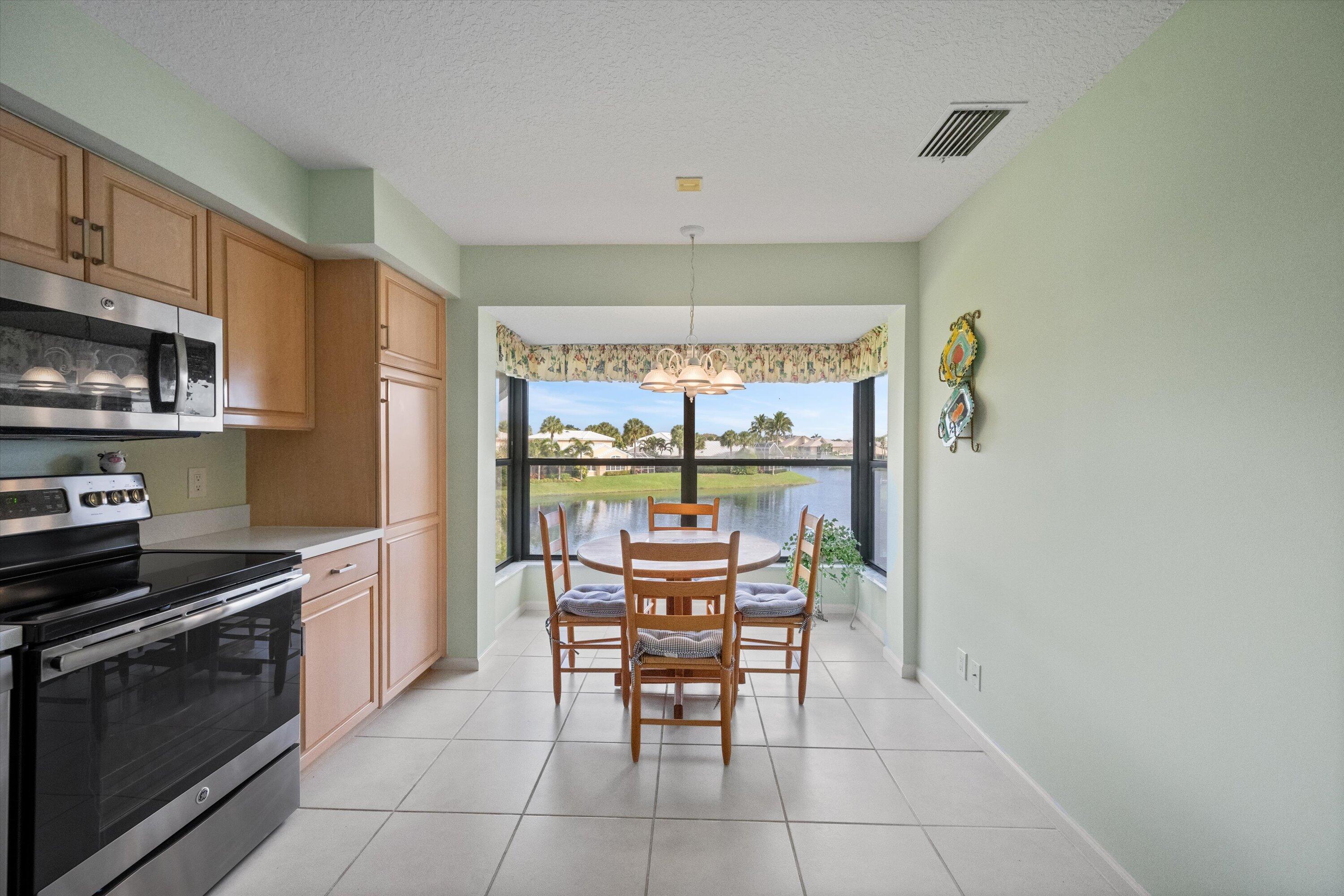 3971 Schooner Pointe Drive, Unit 201 Jupiter, FL 33477 - Photo 14 of 44 a kitchen with stainless steel appliances a stove top oven a sink a dining table and chairs