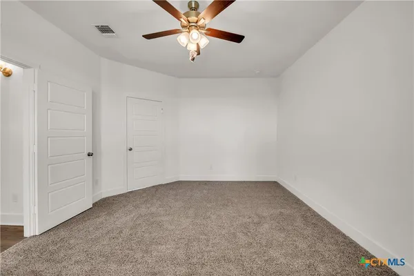 an empty room with chandelier fan
