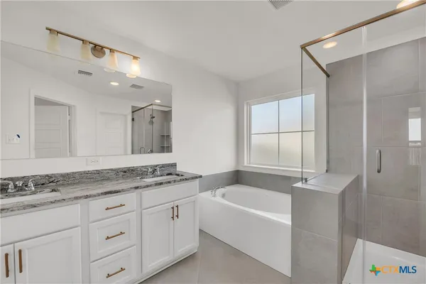 a bathroom with a granite countertop tub sink and mirror