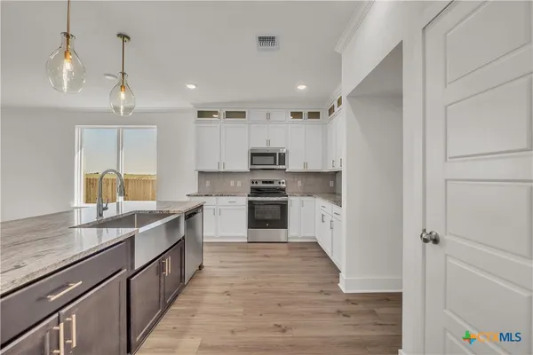 a kitchen with kitchen island white cabinets and stainless steel appliances