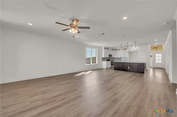 a view of empty room with wooden floor and ceiling fan