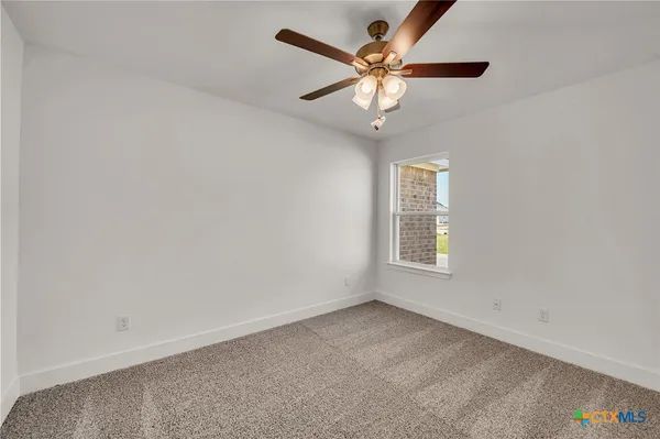 an empty room with a window and a fan