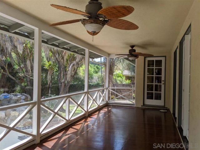 a view of an empty room with wooden floor and windows