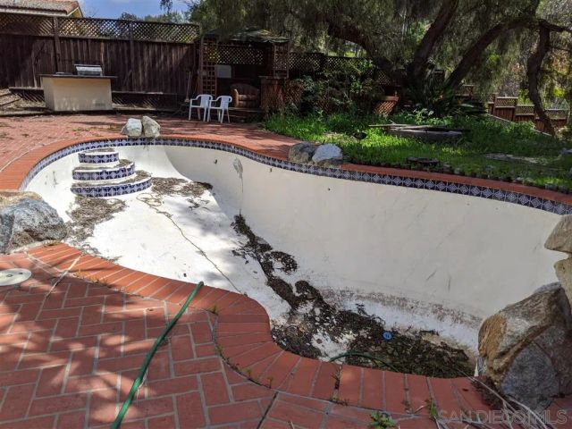 a view of swimming pool with lawn chairs and plants