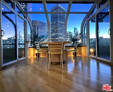 a dining room with wooden floor a glass table and chairs