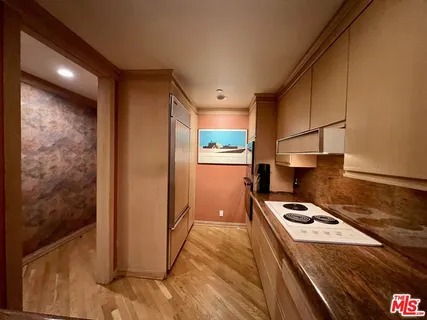 a kitchen with a refrigerator a stove top oven a counter space and wooden floor