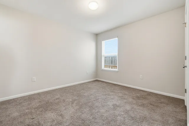 an empty room with wooden floor chandelier and windows