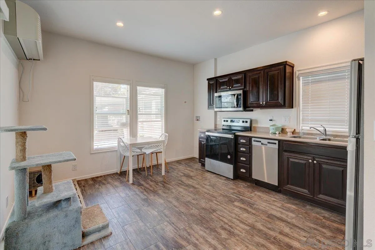 7495 Oakland Road, Unit 32 La Mesa, CA 91942 - Photo 4 of 16 a kitchen with stainless steel appliances kitchen island granite countertop a stove a sink and a microwave