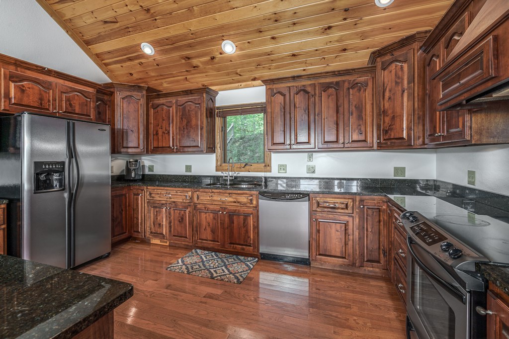 509 Lonesome Pine Road Murphy, NC 28906 - Photo 16 of 70 a kitchen with granite countertop a refrigerator a sink dishwasher a stove and white countertops with wooden floor