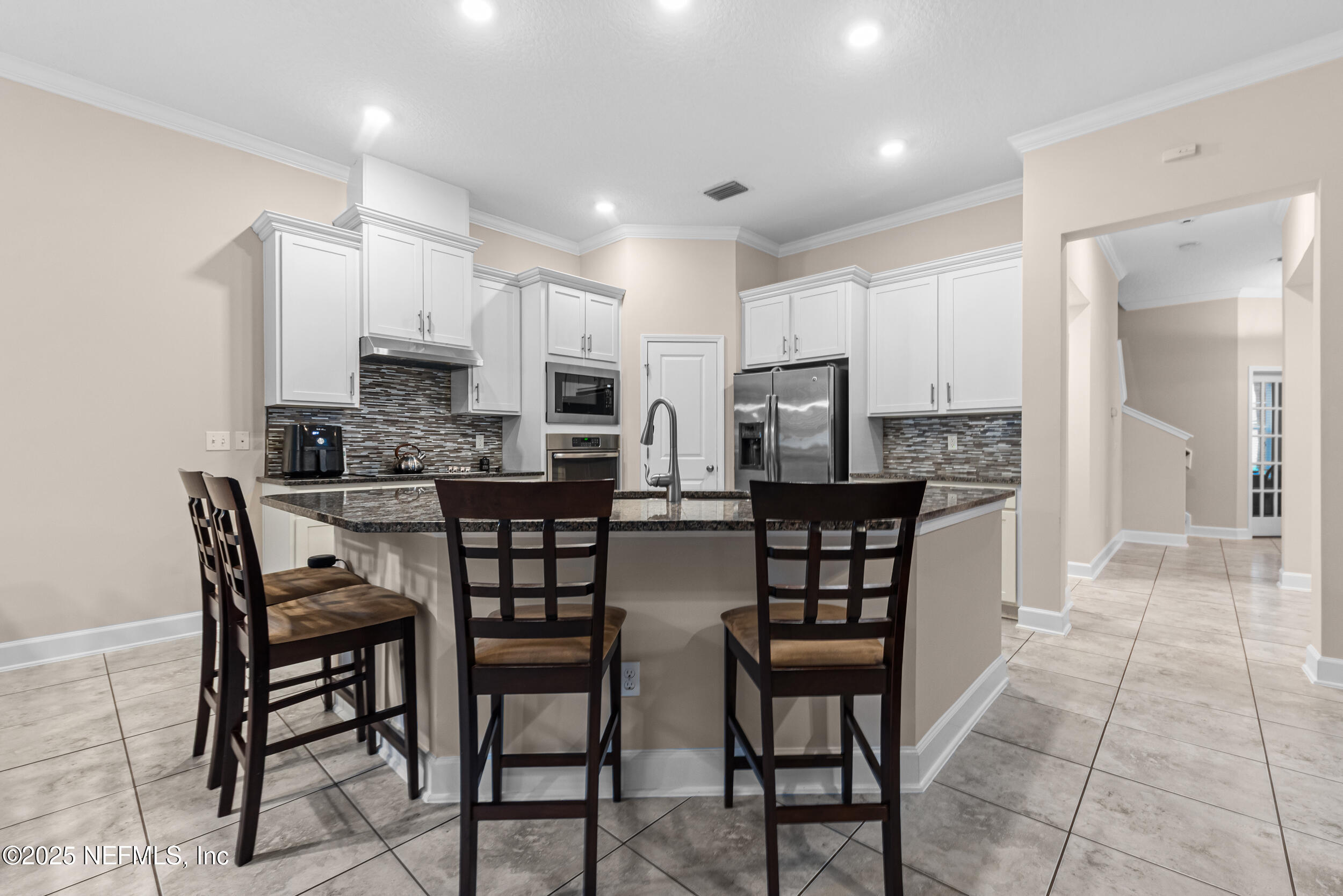 15672 Tisons Bluff Road Jacksonville, FL 32218 - Photo 25 of 42 a kitchen with stainless steel appliances a dining table chairs and a refrigerator