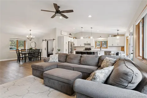 a living room with furniture kitchen view and a chandelier