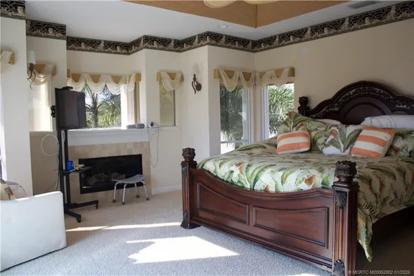 a bedroom with a bed and a large mirror next to a window
