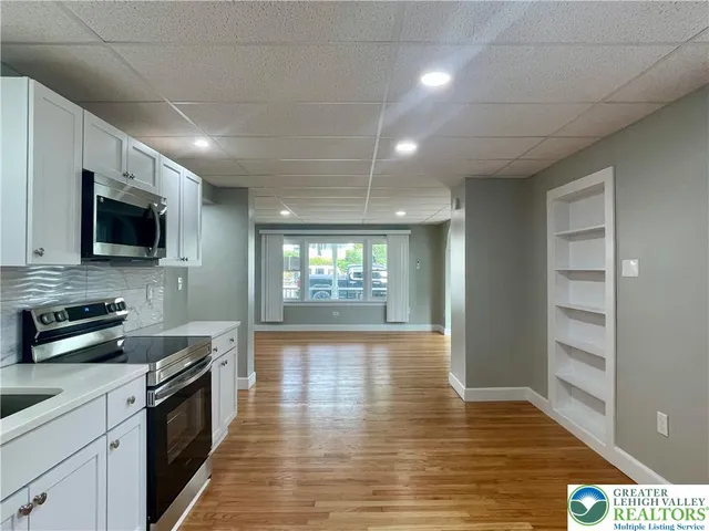 a large kitchen with stainless steel appliances granite countertop a stove and a wooden floors
