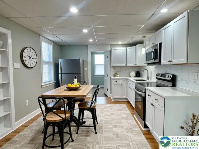 a kitchen with stainless steel appliances granite countertop a table chairs sink and cabinets