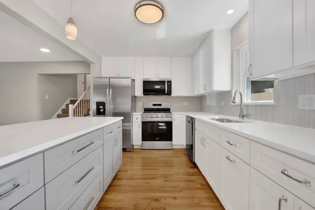 a kitchen with granite countertop a sink stainless steel appliances and white cabinets