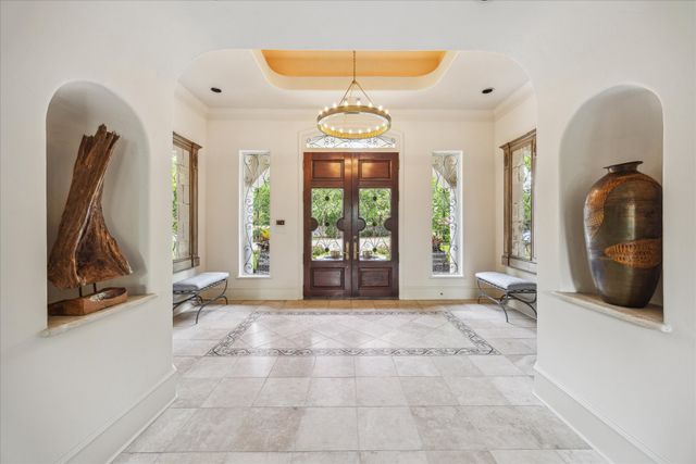 a view of a hallway with windows and chandelier