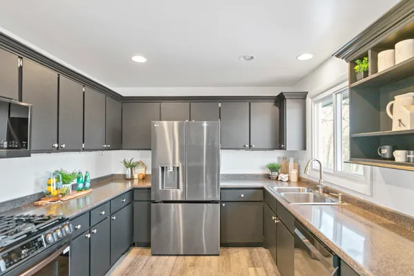 a kitchen with stainless steel appliances granite countertop a refrigerator sink stove and cabinets