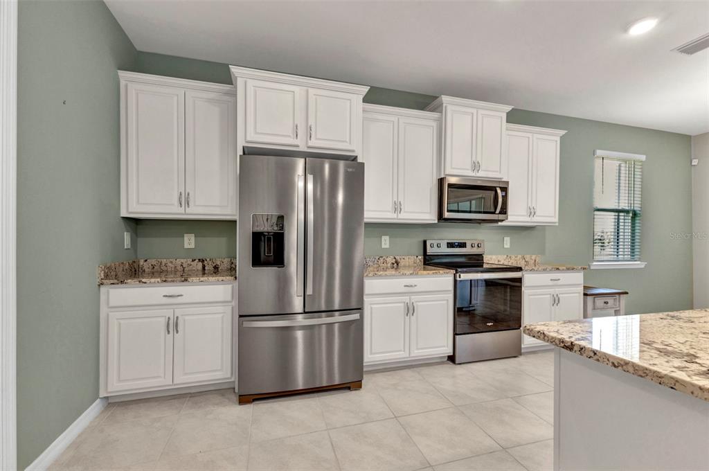 7028 North Plum Tree Punta Gorda, FL 33955 - Photo 23 of 57 a kitchen with granite countertop white cabinets and stainless steel appliances