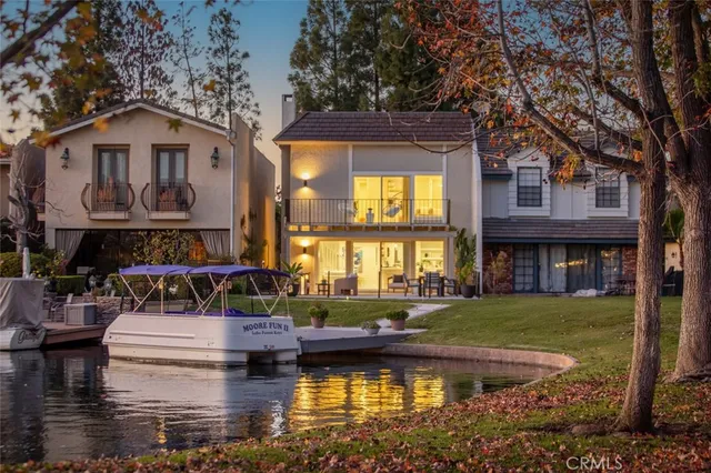 a front view of a house with a garden and lake view