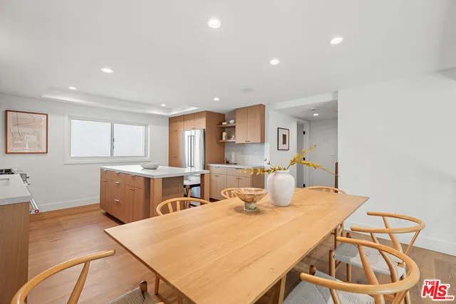 a kitchen with stainless steel appliances granite countertop a stove a sink a refrigerator and white cabinets with wooden floor